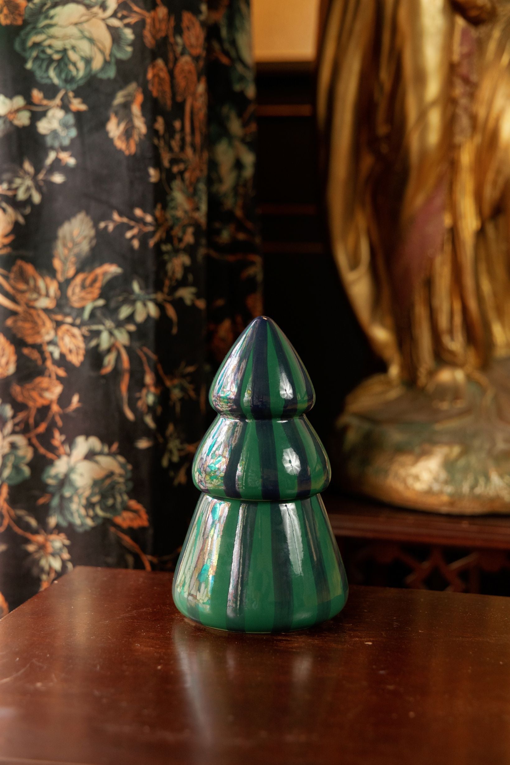Green ceramic tree candle on a dark wood table