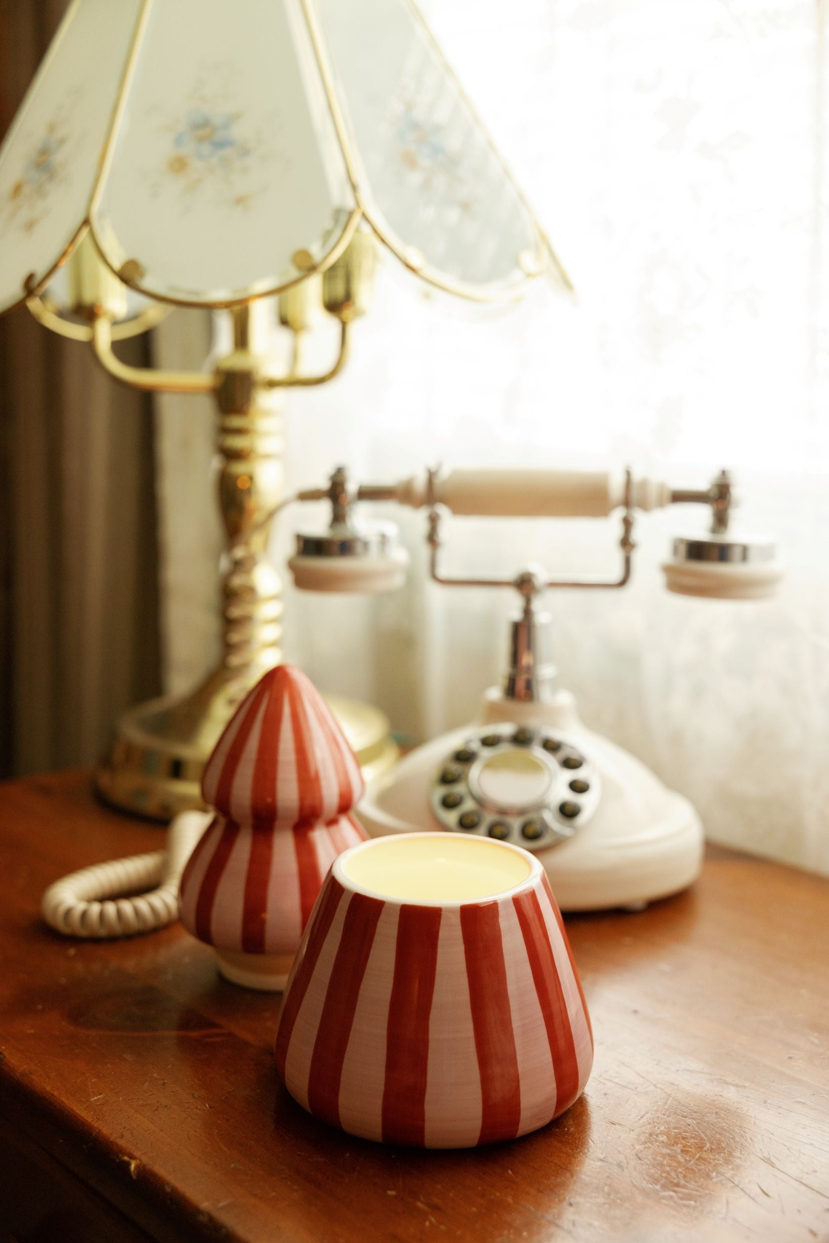 Two red and pink striped tree candles styled on a wooden table
